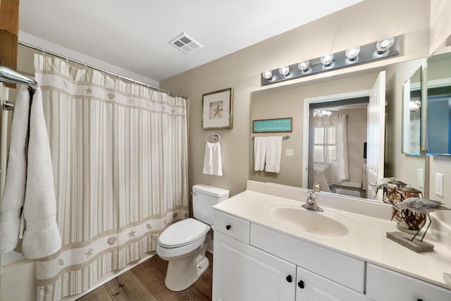 bathroom featuring visible vents, toilet, a shower with curtain, wood finished floors, and vanity