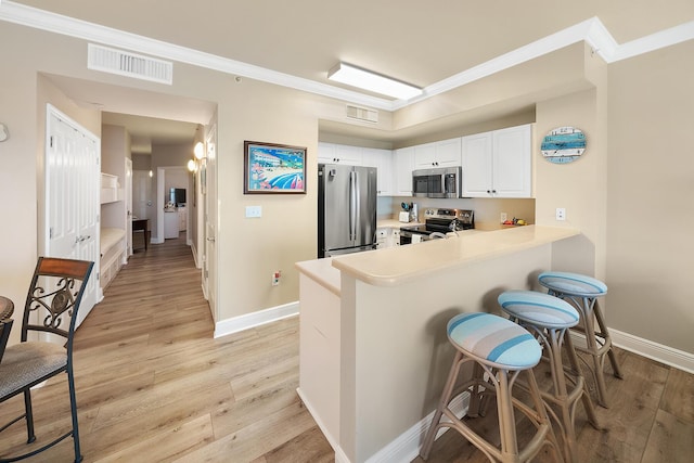 kitchen with stainless steel appliances, a breakfast bar, light wood-style flooring, and visible vents