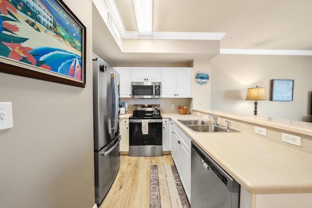 kitchen featuring light wood-style flooring, stainless steel appliances, a peninsula, a sink, and crown molding