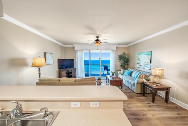 living room with ornamental molding, baseboards, light wood finished floors, and a ceiling fan