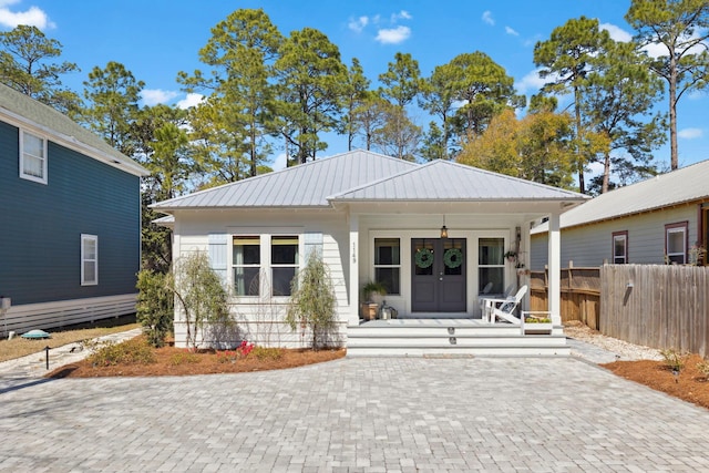 view of front of home featuring a porch, french doors, metal roof, and fence