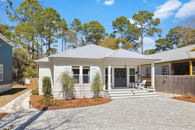 view of front of home with covered porch, french doors, metal roof, and fence