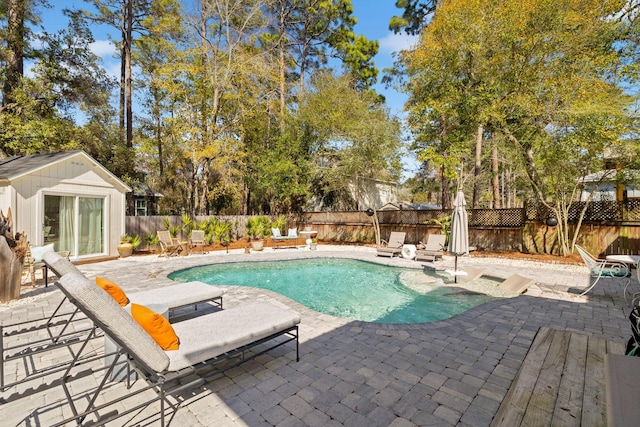 view of swimming pool featuring an outbuilding, a fenced in pool, a patio, and a fenced backyard