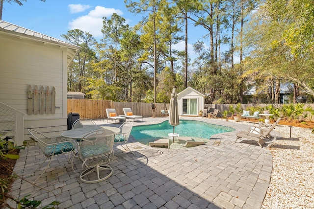 view of pool with a patio, a fenced backyard, a fenced in pool, and an outbuilding