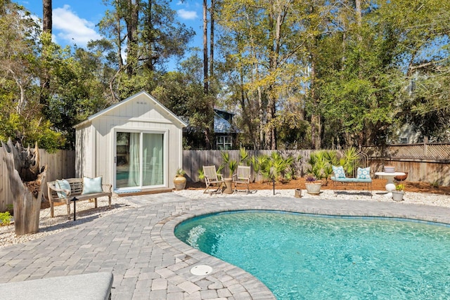 view of pool featuring an outdoor structure, a patio area, a fenced in pool, and a fenced backyard