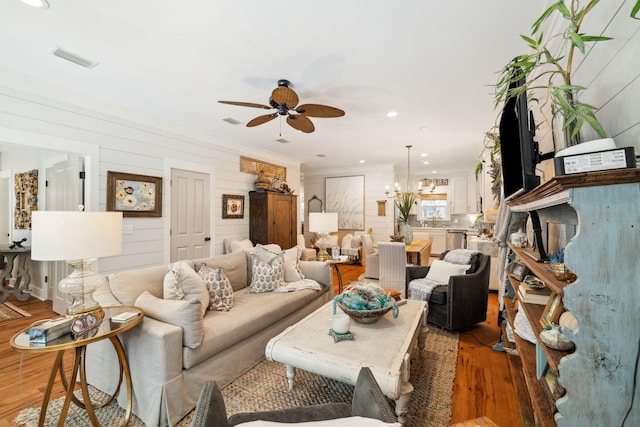 living area featuring visible vents, light wood finished floors, recessed lighting, ornamental molding, and ceiling fan with notable chandelier