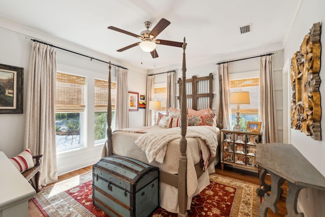 bedroom featuring visible vents, ornamental molding, a ceiling fan, and wood finished floors