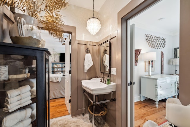 ensuite bathroom with ornamental molding, ensuite bathroom, wood finished floors, an inviting chandelier, and vanity