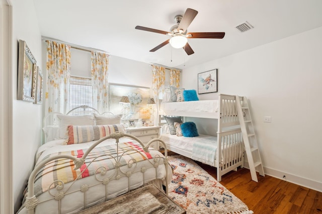 bedroom with ceiling fan, visible vents, baseboards, and wood finished floors