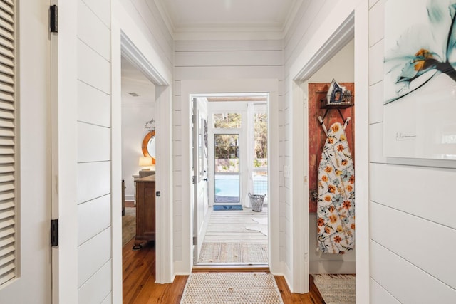 foyer entrance featuring light wood finished floors, wood walls, and ornamental molding