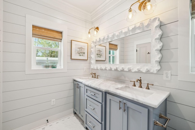 bathroom with a sink, wood walls, double vanity, and ornamental molding