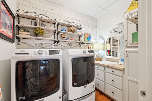 washroom featuring wooden walls, independent washer and dryer, light wood-style flooring, and laundry area