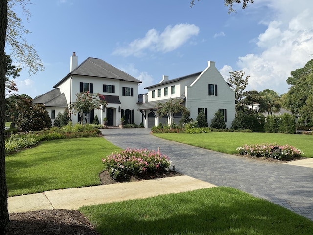 view of front of home featuring a front lawn, decorative driveway, and a chimney