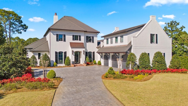 view of front of house with decorative driveway, a chimney, and a front lawn