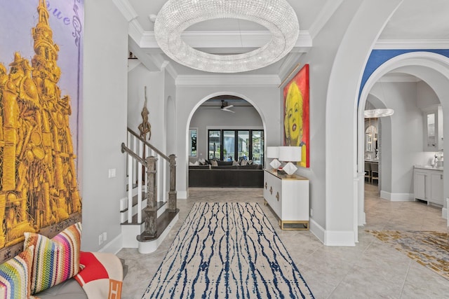 entrance foyer featuring arched walkways, stairway, baseboards, and crown molding