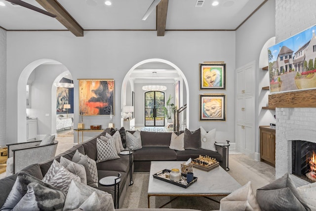 living area with a brick fireplace, baseboards, arched walkways, and beamed ceiling