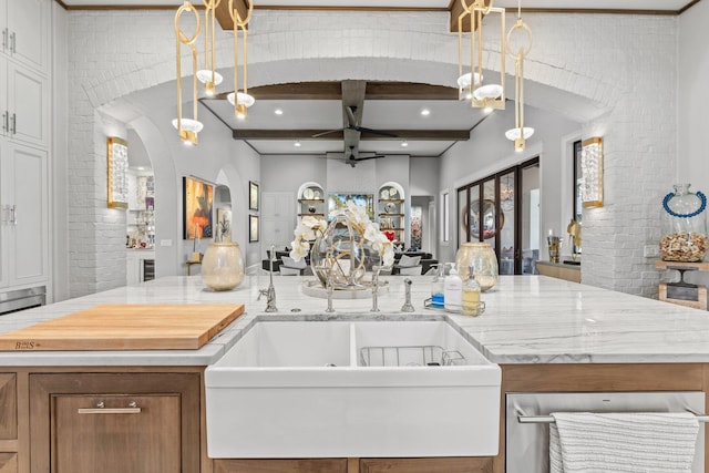 kitchen featuring pendant lighting, open floor plan, a sink, and brick wall