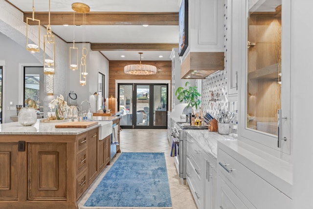 kitchen with light tile patterned floors, brown cabinets, beamed ceiling, high end stove, and a sink