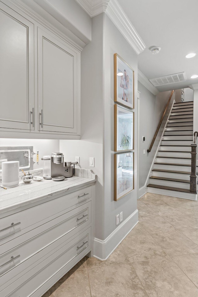 bar with ornamental molding, visible vents, stairway, and baseboards