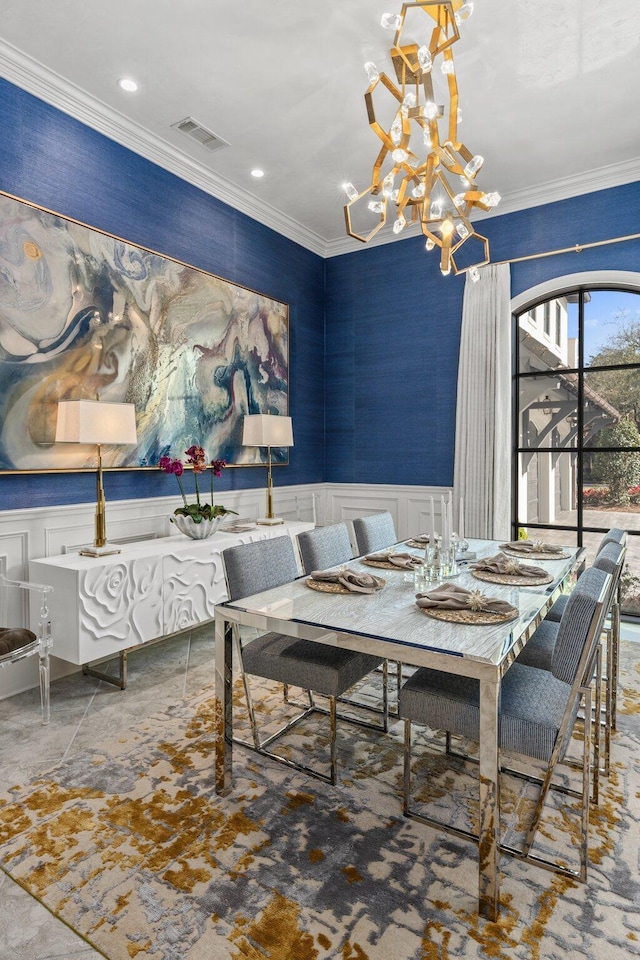 dining room with a notable chandelier, wainscoting, visible vents, and crown molding