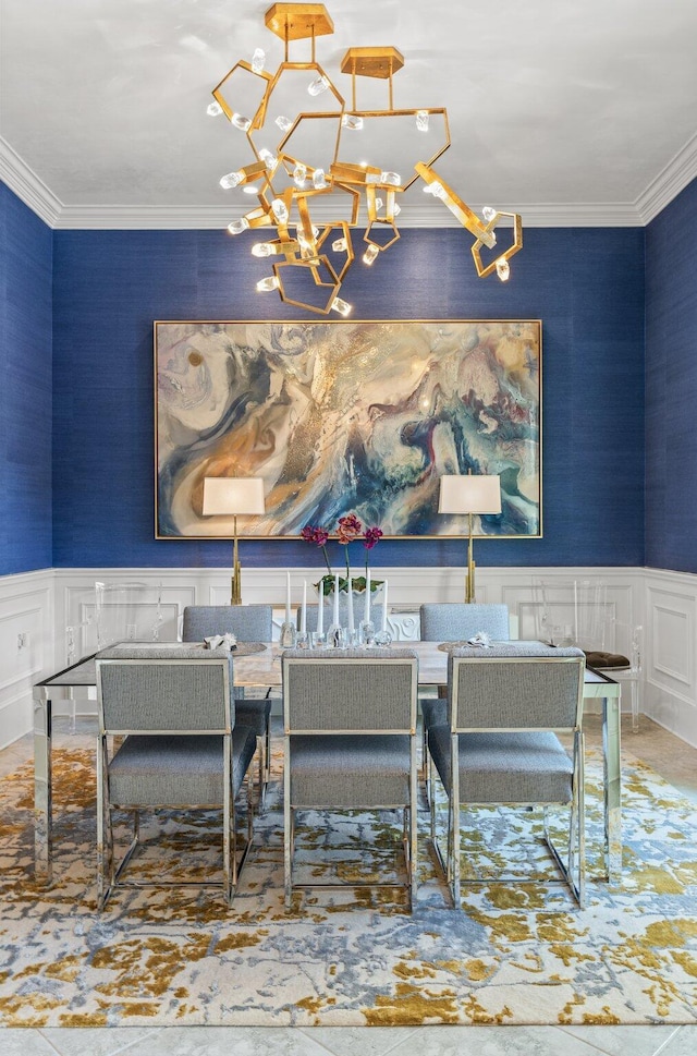 dining area with ornamental molding, wainscoting, a decorative wall, and an inviting chandelier