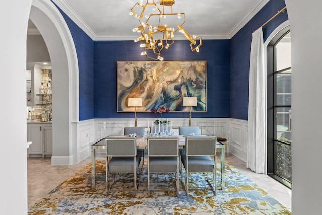 dining area featuring a chandelier, arched walkways, a wainscoted wall, and ornamental molding