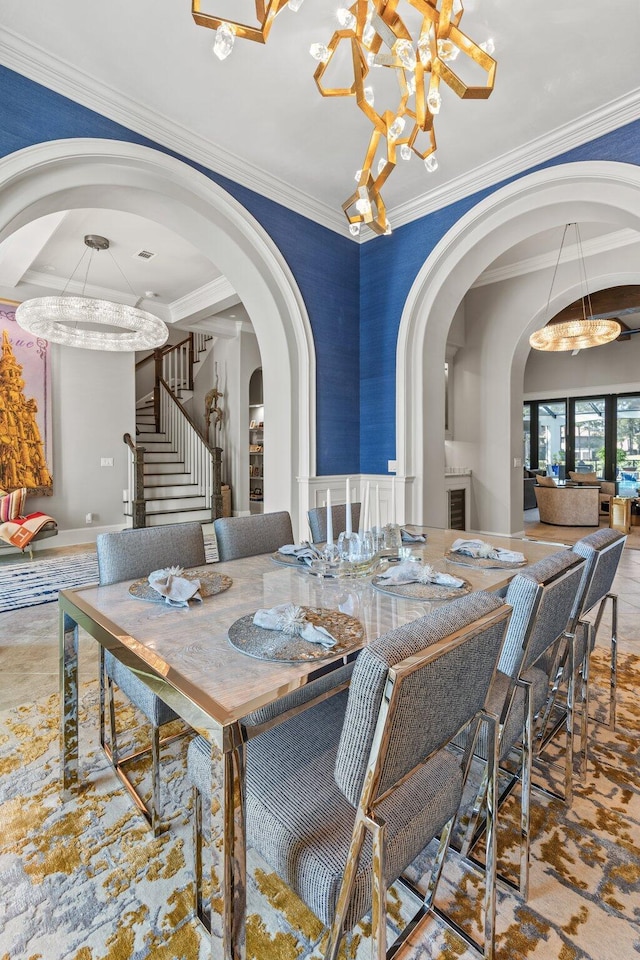 dining room with ornamental molding, arched walkways, a chandelier, and stairs