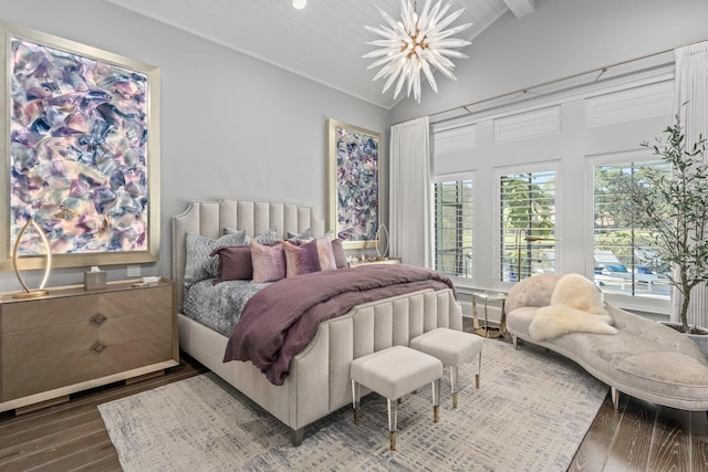 bedroom with vaulted ceiling, wood finished floors, multiple windows, and a chandelier