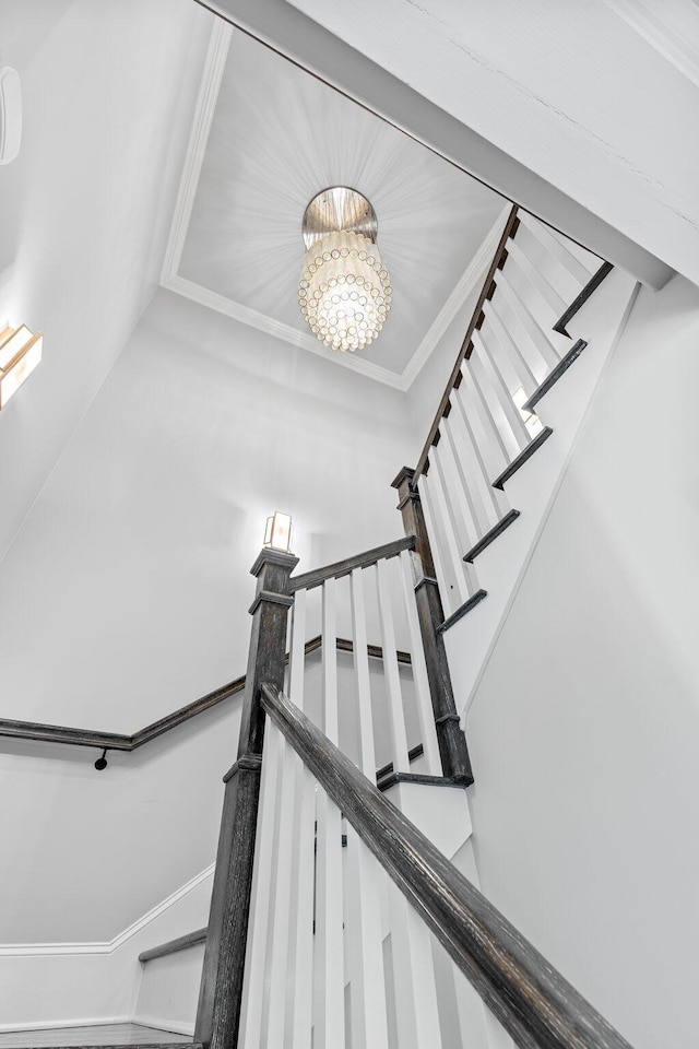 staircase with ornamental molding and an inviting chandelier