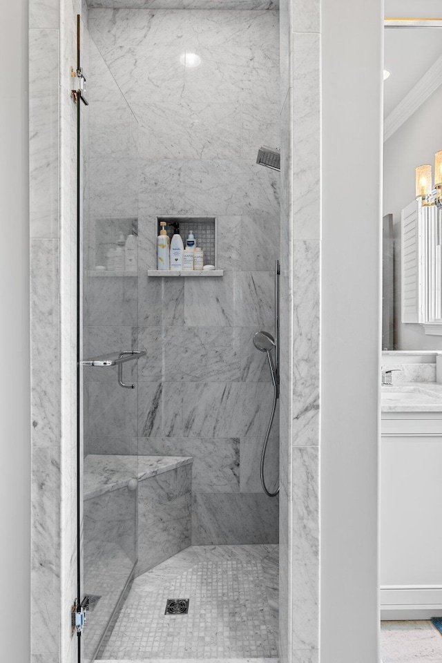 full bath with crown molding, vanity, and a marble finish shower