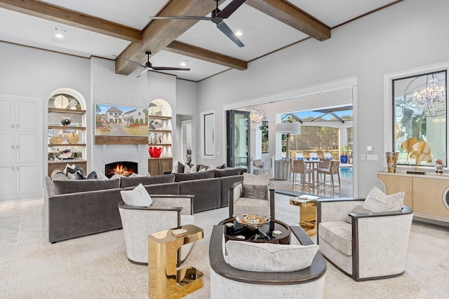 living room featuring a large fireplace, a sunroom, ceiling fan, built in shelves, and beam ceiling