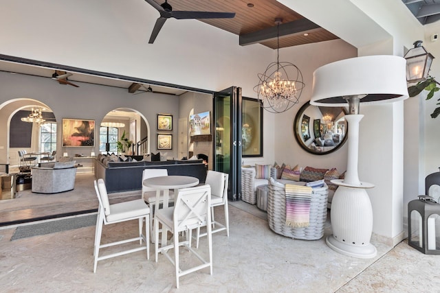 dining area featuring arched walkways, beamed ceiling, ceiling fan with notable chandelier, and wooden ceiling