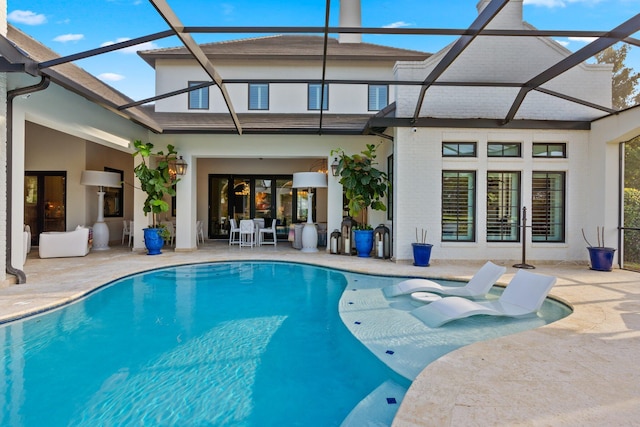 exterior space featuring an outdoor pool, glass enclosure, a patio, and brick siding