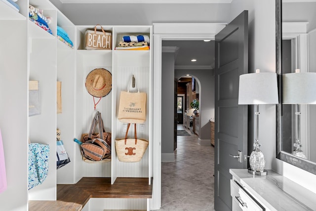 mudroom featuring ornamental molding, arched walkways, and tile patterned flooring