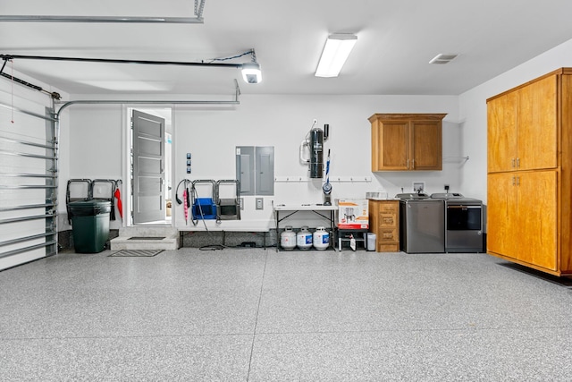 garage with electric panel, visible vents, a garage door opener, and independent washer and dryer