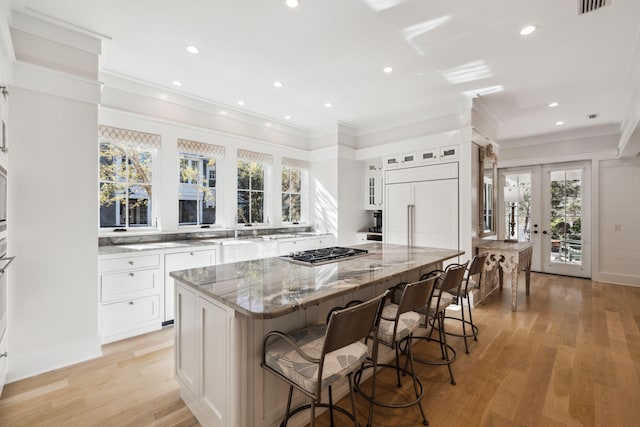 254 E Yacht Pond Ln, Watersound, FL 32461 - kitchen with light wood finished floors, stainless steel gas cooktop, paneled built in refrigerator, light stone counters, and a center island