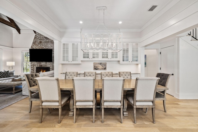 254 E Yacht Pond Ln, Watersound, FL 32461 - dining space with a fireplace, light wood-style flooring, visible vents, and an inviting chandelier