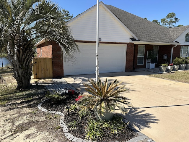 view of front facade with brick siding, concrete driveway, a garage, and a shingled roof