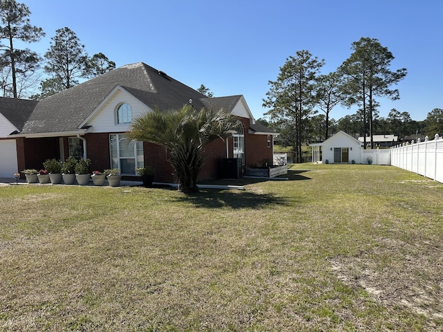 view of side of home featuring a yard, fence, and brick siding