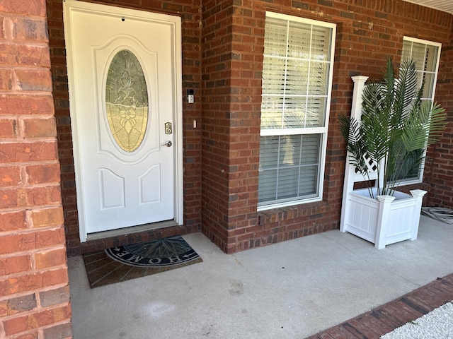 doorway to property featuring brick siding and covered porch