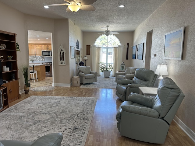 living area featuring light wood-style flooring, ceiling fan, and a textured wall