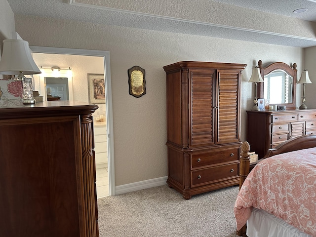 bedroom featuring light carpet, ensuite bathroom, a textured ceiling, baseboards, and a textured wall