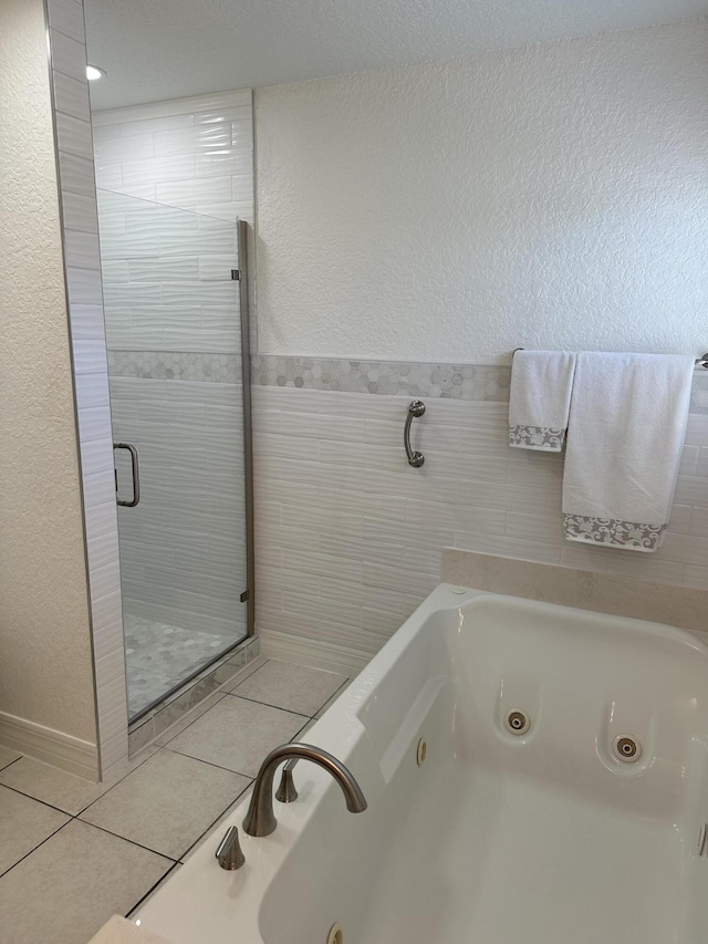 full bath featuring tile patterned flooring, a shower stall, a jetted tub, and tile walls