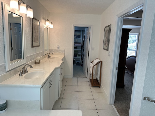 bathroom with a sink, a walk in closet, double vanity, and tile patterned flooring