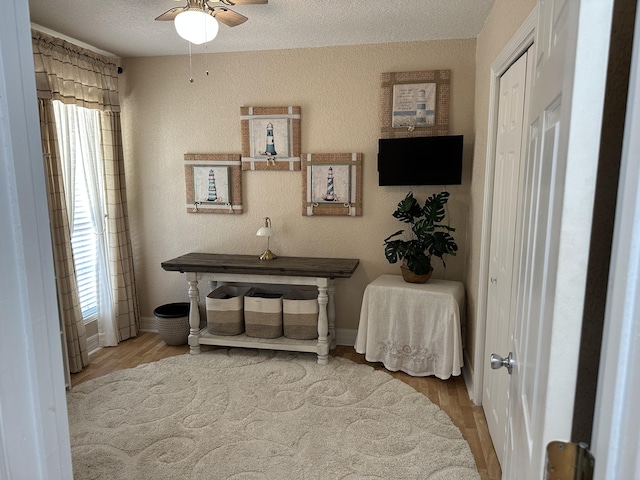 interior space with wood finished floors, a textured ceiling, ceiling fan, and a textured wall