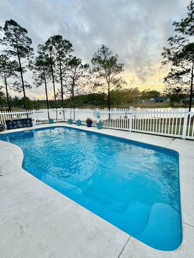 pool at dusk with a fenced in pool, a fenced backyard, and a patio area