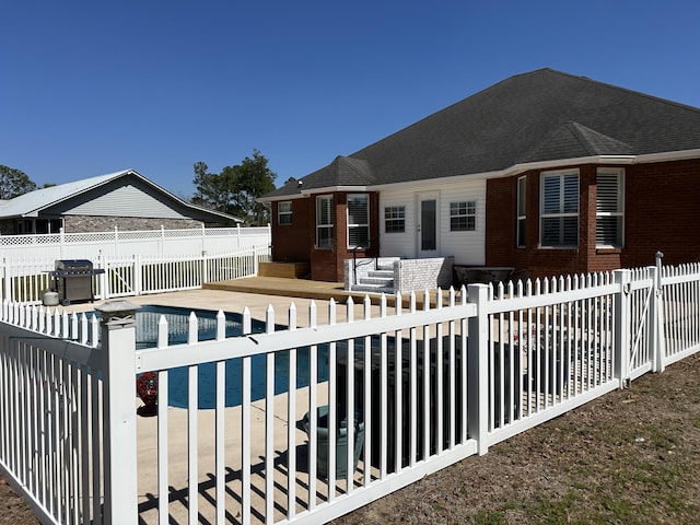 exterior space with a fenced in pool, brick siding, a fenced backyard, and a patio area