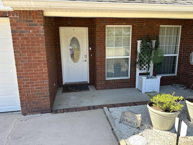 doorway to property with brick siding and a porch