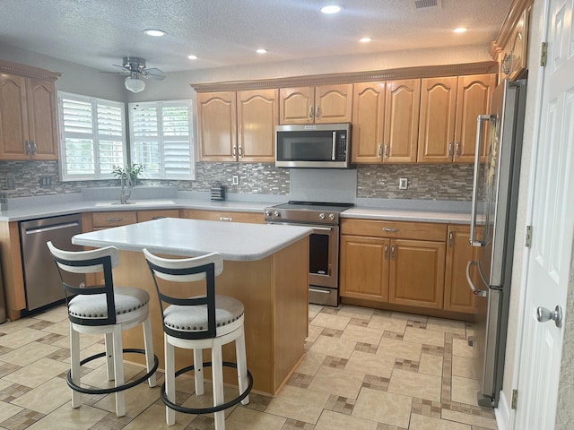 kitchen with a center island, a breakfast bar, light countertops, stainless steel appliances, and a sink