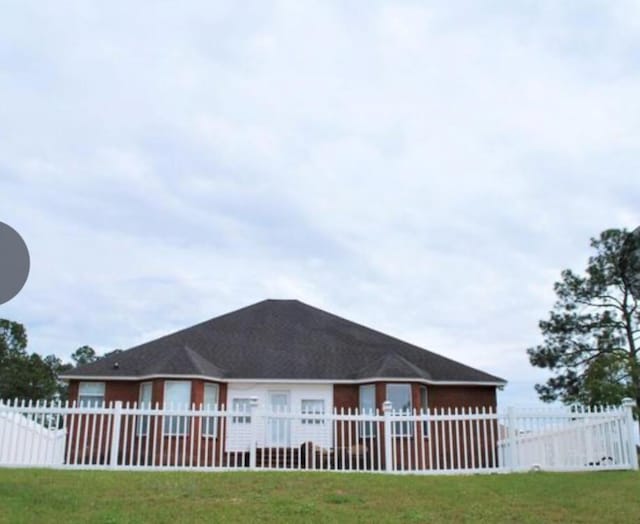 rear view of house with a fenced front yard and a yard